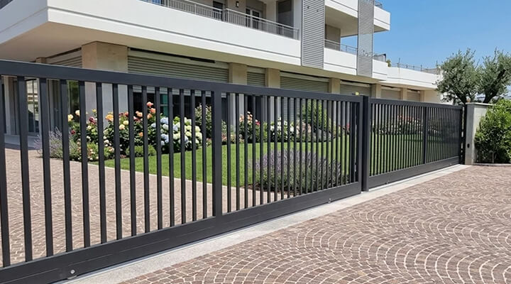Portail coulissant d'un parking de copropriété devant un immeuble : ouvrir son garage Clemsa avec son smartphone